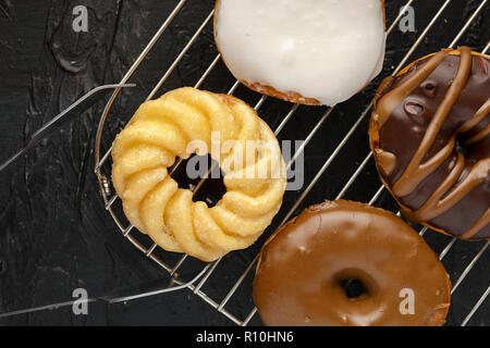 An assortment of glazed and chocolate covered doughnuts sit on a wire rack. Stock Photo