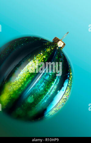 Close up of glittery green Christmas bauble, pale blue background Stock Photo