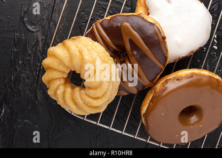 An assortment of glazed and chocolate covered doughnuts sit on a wire rack. Stock Photo