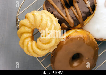 An assortment of glazed and chocolate covered doughnuts sit on a wire rack. Stock Photo