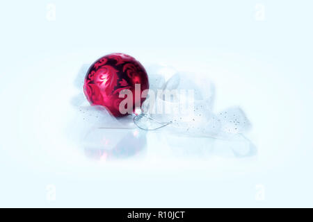 Deep red Christmas bauble with sheer white ribbon in center of image, space for copy Stock Photo