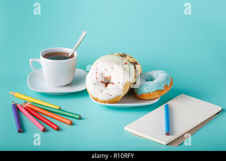Four donuts on saucer with cup of tea. Aquamarine background Stock Photo
