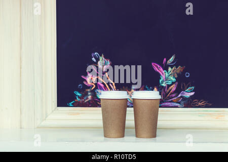 Two carton paper cups with cap at the bar with autumn pattern Stock Photo