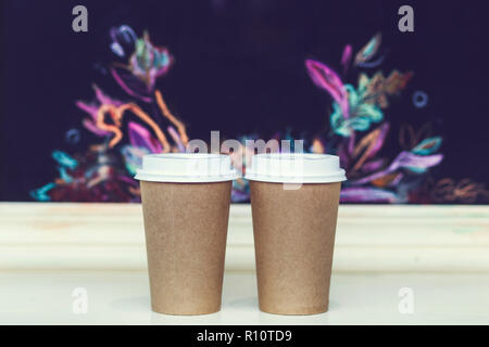 Two carton paper cups with cap at the bar with autumn pattern Stock Photo