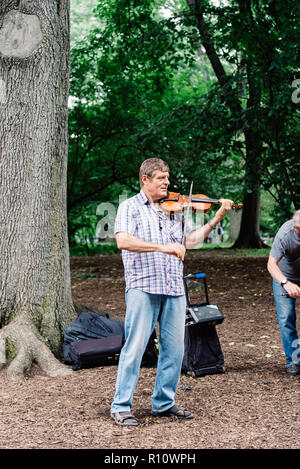 New York City, USA - June 23, 2018: Man playing violin in Central Park a cloudy day of summer Stock Photo