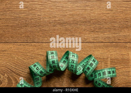 Green tape-line for measuring on wooden table as work  bench with blank copy text area Stock Photo