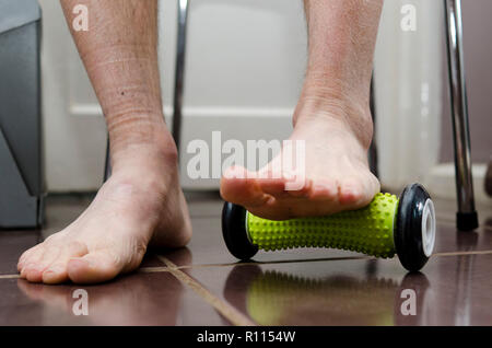 Plantar Fasciitis. Sufferer using a foot roller at home for treatment.