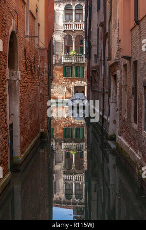 Narrow canal with old brick buildings on either side Venice Italy Stock Photo