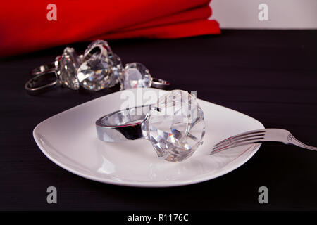 Big diamond rings on the white plate. In the background a bunch of big rings. Stock Photo