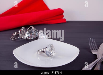 Big diamond ring on the white plate. In the background a bunch of rings. Stock Photo