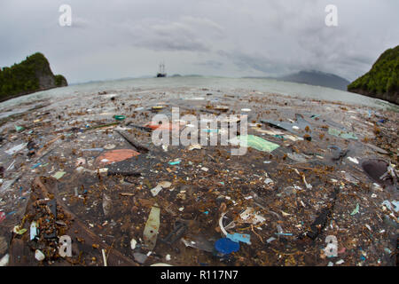 Discarded plastic bits and pieces drift close to an island in Raja Ampat, Indonesia. Plastics break down into tiny pieces and enter the food chain. Stock Photo