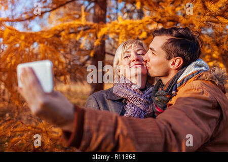 Middle-aged woman taking selfie with her adult son using phone. Family values Stock Photo