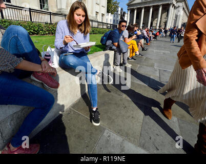 People relaxing at lunchtime in front of the National Gallery in Trafalgar Square, London, England, UK.