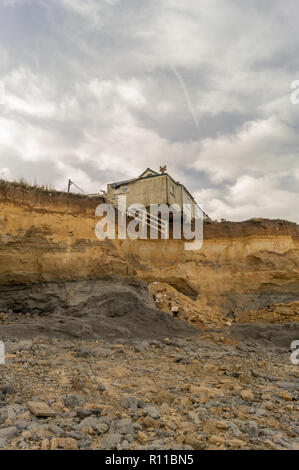 House on edge of cliff washed away by the sea, coastal erosion, global warming, rising sea levels, Happisburgh Norfolk, UK. distant view Stock Photo
