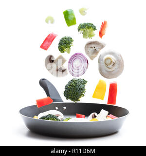 Fresh  vegetables ready for cooking flying into a pan isolated on white Stock Photo