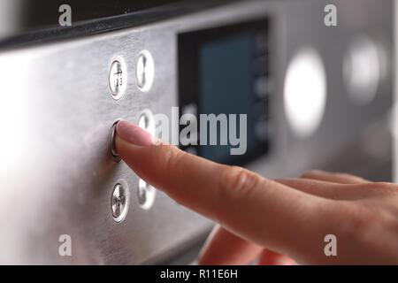Close up female hand while using the microwave in her kitchen Stock Photo