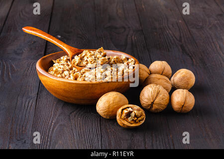 Walnut oil from walnut kernels in a bottle , walnut shells around it and whole walnuts on the wooden table Stock Photo