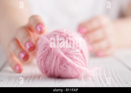 Knitting yarn twisted in clews on wooden background, light pink Stock Photo