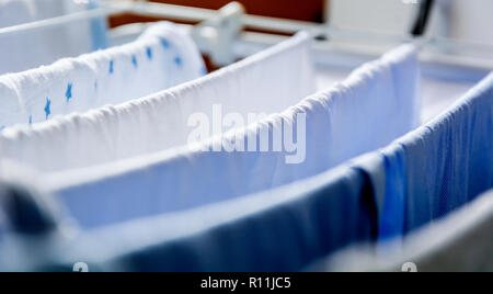 Different types of clothes left hanging to dry on a clotheshorse Stock Photo