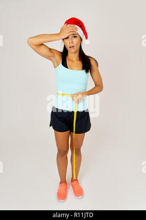 Sad unhappy young latin woman worried of gaining weight after Christmas in consequences of unhealthy eating lifestyle during christmas loss weight and Stock Photo