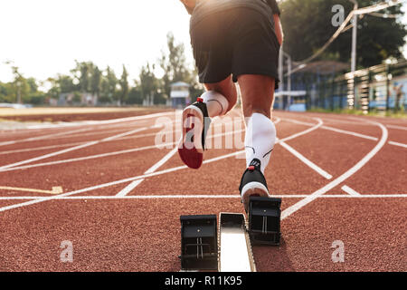 Cropped photo of handsome strong young sportsman running outdoors. Stock Photo