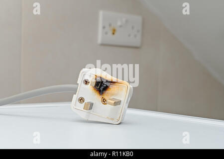 Burned 250V uk style socket and converter. Improper use of AC Power Plugs and Sockets cause of short circuit and fires at home Stock Photo