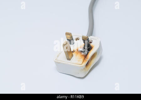 Burned 250V uk style socket and converter isolated on white. Improper use of AC Power Plugs and Sockets cause of short circuit and fires at home Stock Photo