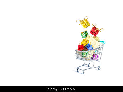 Multicolored gift boxes with beautiful golden bows fall into a gift-filled shopping cart isolated on a white background Stock Photo