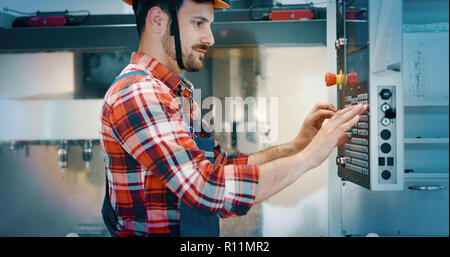 Industry Worker entering data in CNC machine at factory Stock Photo