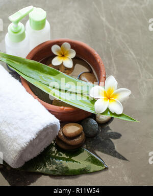 Spa or wellness setting with tropical flowers, leaves, bottles and white towel Stock Photo