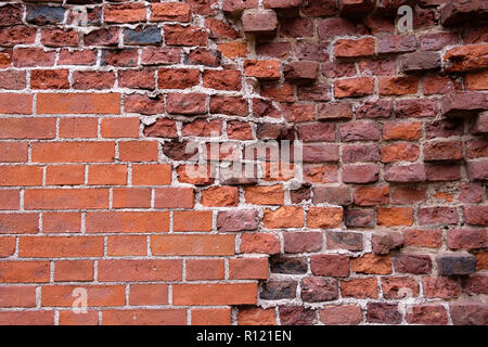 The damaged red brick wall of an ancient castle. Partially restored while preserving the destroyed elements of the wall Stock Photo