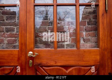 Red brick wall behind glass door or window. Strange door into the wall Stock Photo