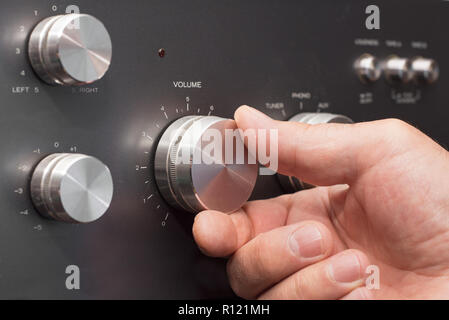 Hand turning up the volume in a stereo Stock Photo