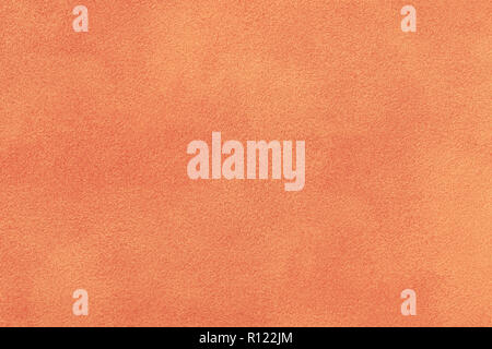 Orange matte background of suede fabric, closeup. Velvet texture of seamless coral leather. Felt materisl macro. Stock Photo
