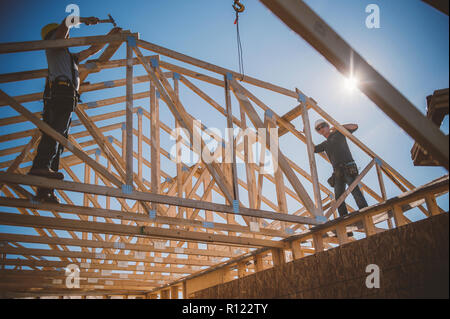 Builders working on rooftop frame of building Stock Photo