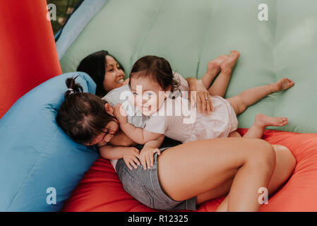 Mother and daughters playing on bouncy castle Stock Photo