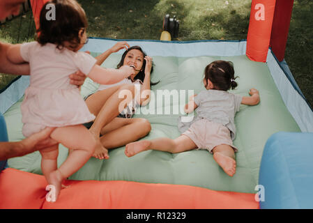 Mother and daughters playing on bouncy castle Stock Photo