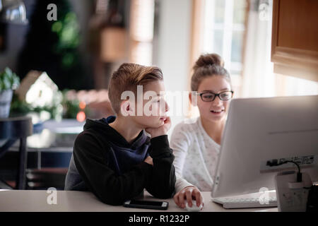 Siblings using computer at home Stock Photo