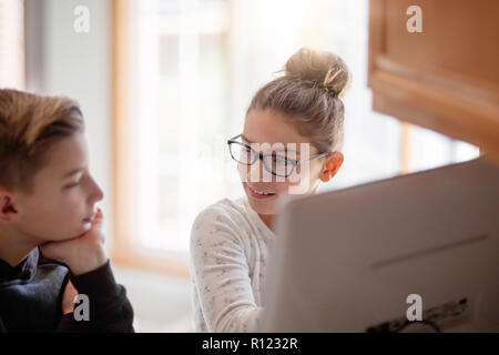 Siblings using computer at home Stock Photo