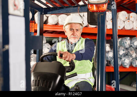 Senior worker on the forklift in a warehouse of a logistics company Stock Photo