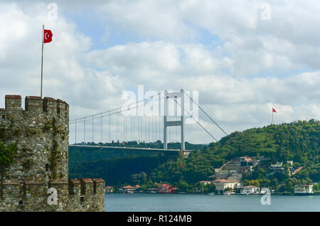 View from Rumeli Hisar castle to the Bosphorus bridge and the Asian part of Istanbul. Turkish flags on the tower and on the other side Stock Photo