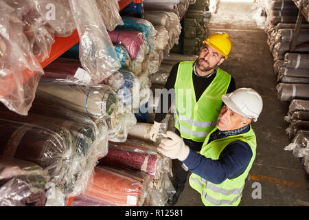 Two warehouse workers in the carpet warehouse make delivery together for shipping Stock Photo