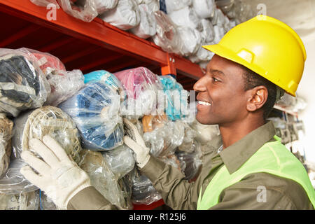 Young man as a worker or warehouse specialist in the carpet warehouse in a warehouse Stock Photo