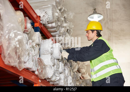 Young worker or specialist warehouse inspects inventory in carpet warehouse Stock Photo