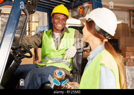 Two warehouse workers discuss a delivery in the warehouse of the freight forwarder Stock Photo