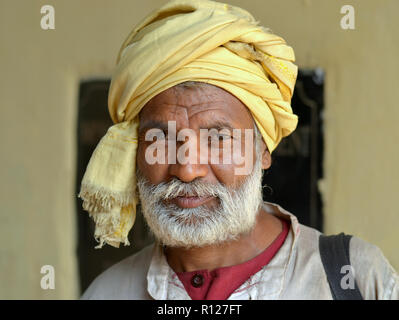 Elderly Indian Hindu pilgrim wears a yellow turban at Kolkata's Shovabazaar Ghat and poses for the camera. Stock Photo