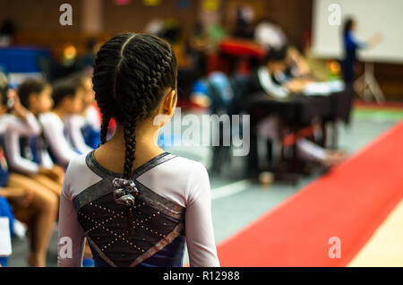 Little gymnast waving to the public in a competition at the stadium Stock Photo