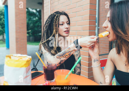 Girlfriends sharing ice cream at cafe Stock Photo