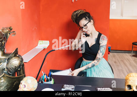Tattooist talking on mobile phone in parlour Stock Photo