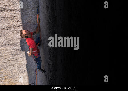 Rock climber in shadow of rock Stock Photo